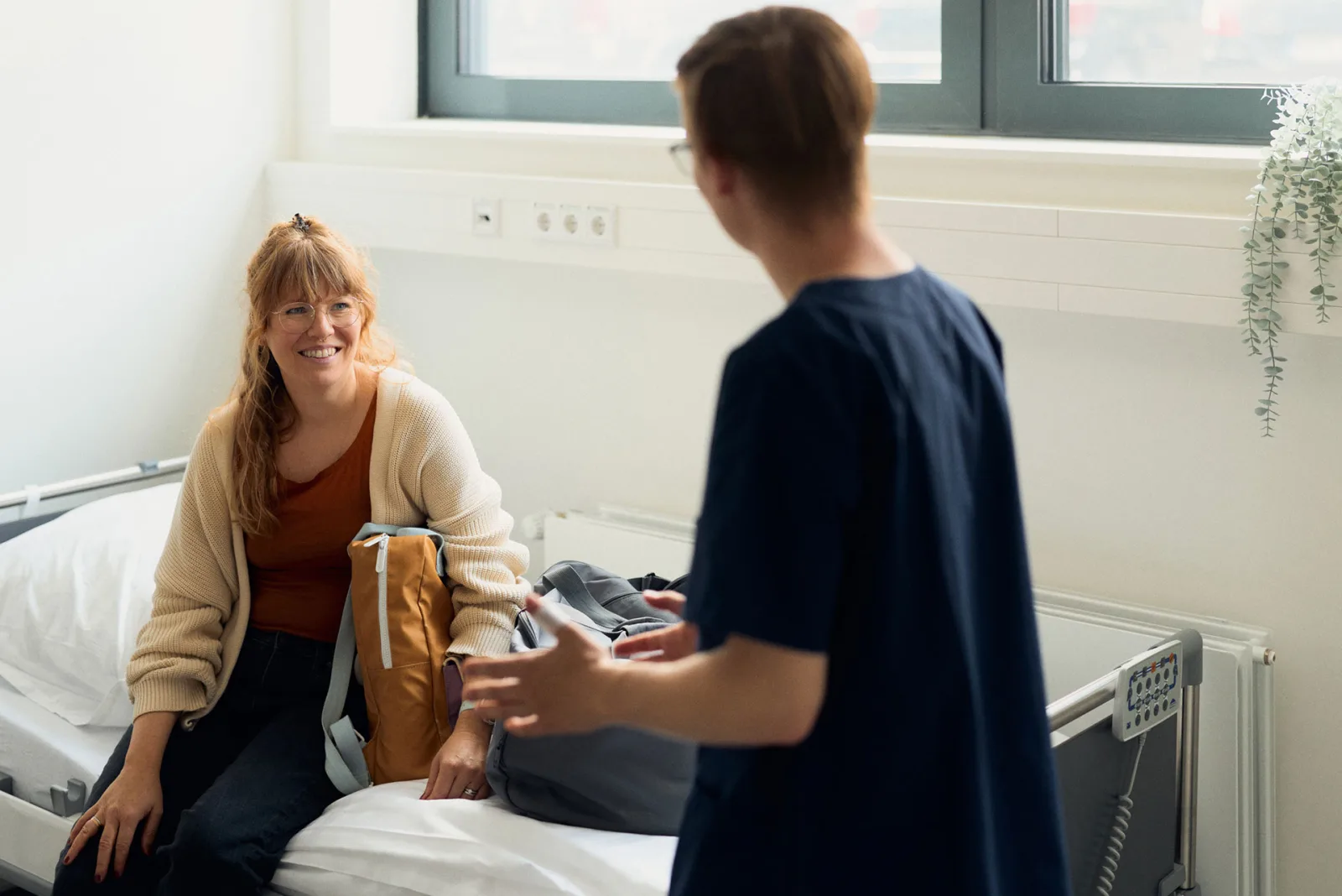 A doctor in conversation with a simulated person in a consultation. The two sit facing each other at a desk.